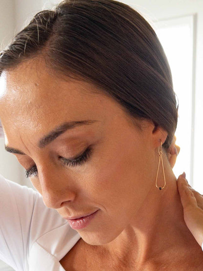 model wearing gold teardrop earrings with tiny black diamond