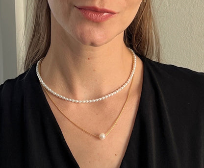 close up of model wearing floating pearl necklace along with freshwater pearl strand necklace
