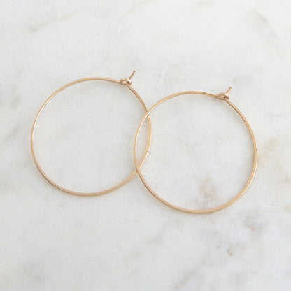 Gold hoop earrings on a white marble surface