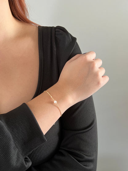model wearing tiny pearl bracelet in gold