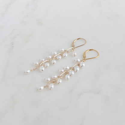 grape pearl earrings on leverback ear wires layng flat on marble surface