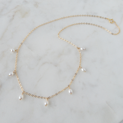 Gold necklace with pearls on a marble surface