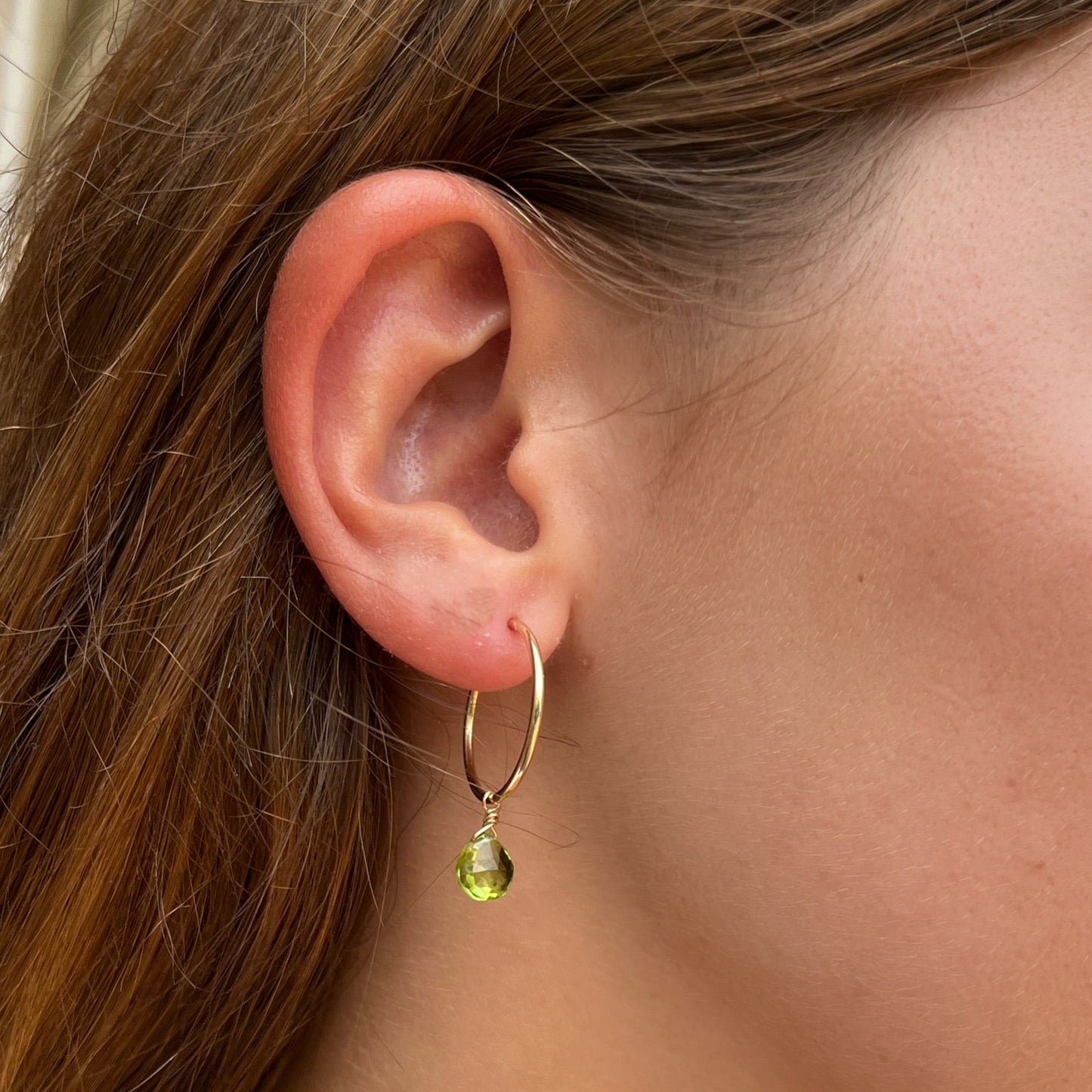 close up of model ear wearing 20mm gold hoop earring with peridot gemstone dangles