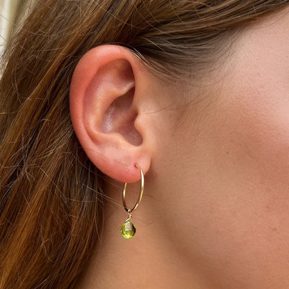 close up of model ear wearing 20mm gold hoop earring with peridot gemstone dangles