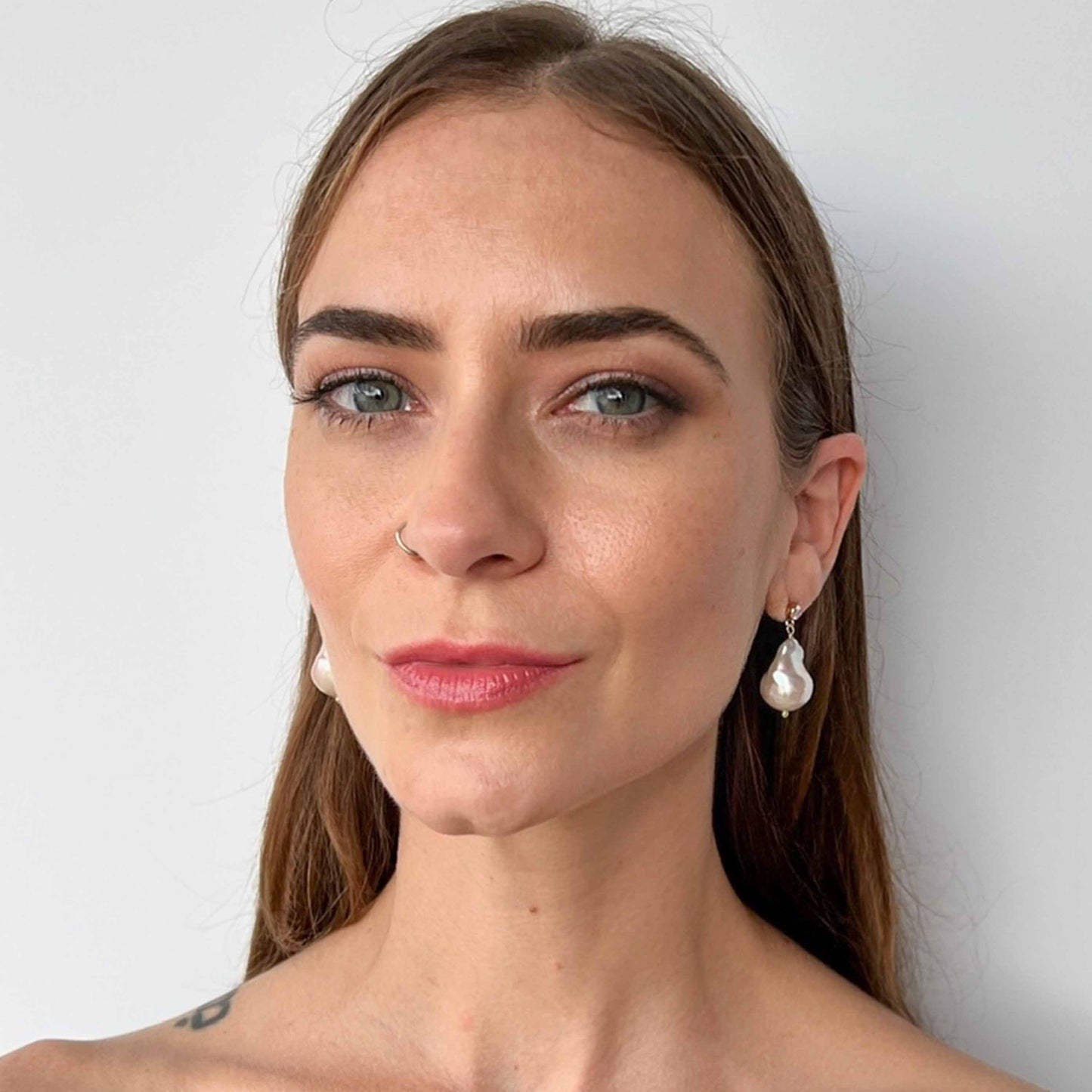 Model wearing large baroque pearl earrings on cz stud earrings