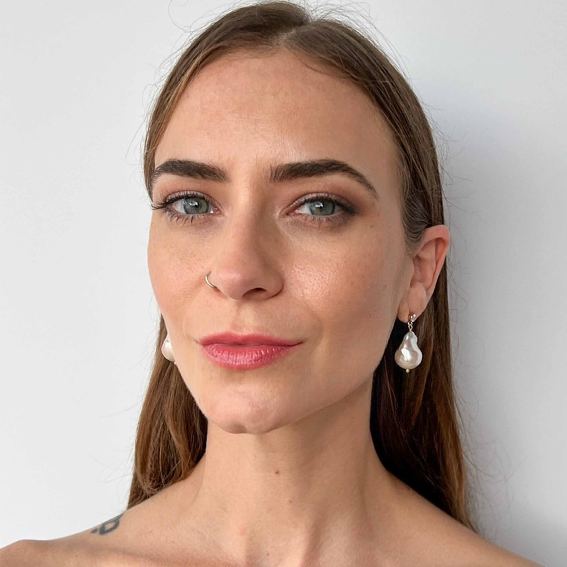Model wearing large baroque pearl earrings on cz stud earrings