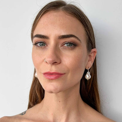 Model wearing large baroque pearl earrings on cz stud earrings