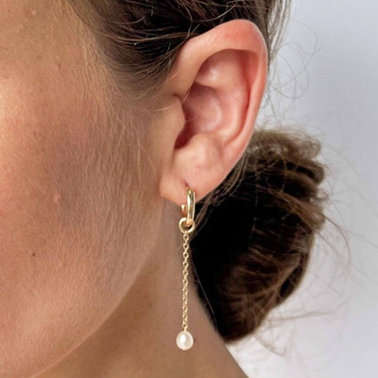 close up of model wearing huggie hoop earrings with pearl dangle
