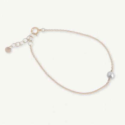 Gold chain bracelet with a saltwater akoya pearl on a white background