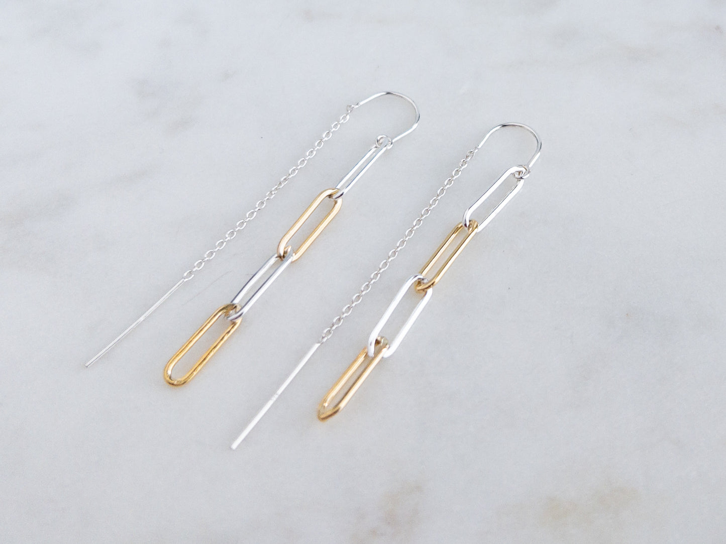 pair of mixed metal threader earrings on marble surface.  Threader is sterling silver and paperclip chain links are sterling silver and 14k gold filled