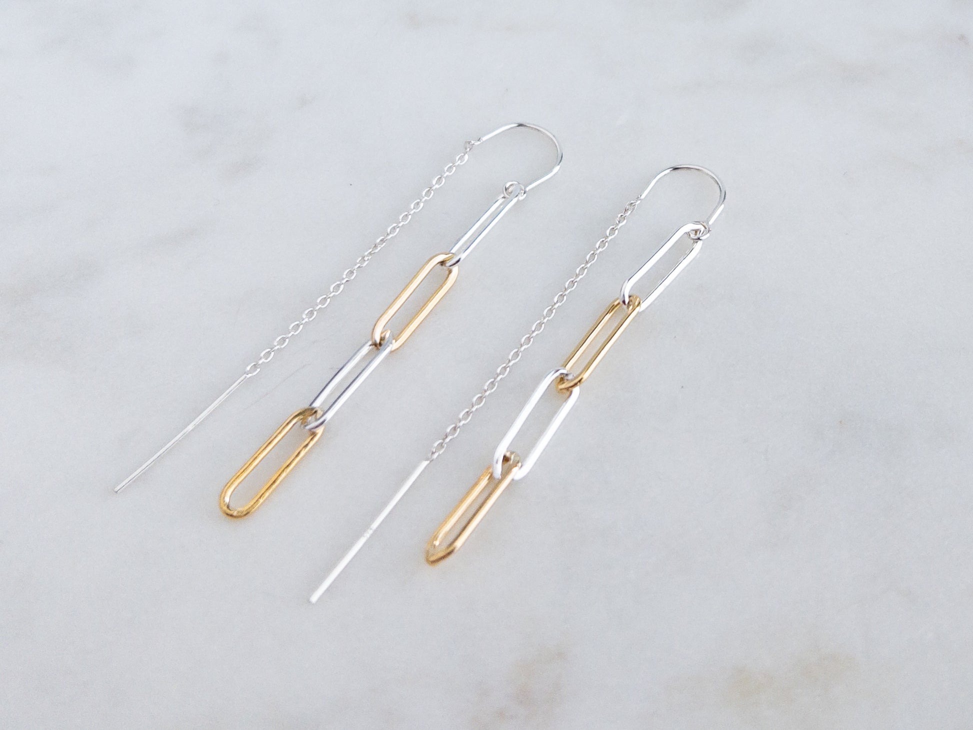 pair of mixed metal threader earrings on marble surface.  Threader is sterling silver and paperclip chain links are sterling silver and 14k gold filled