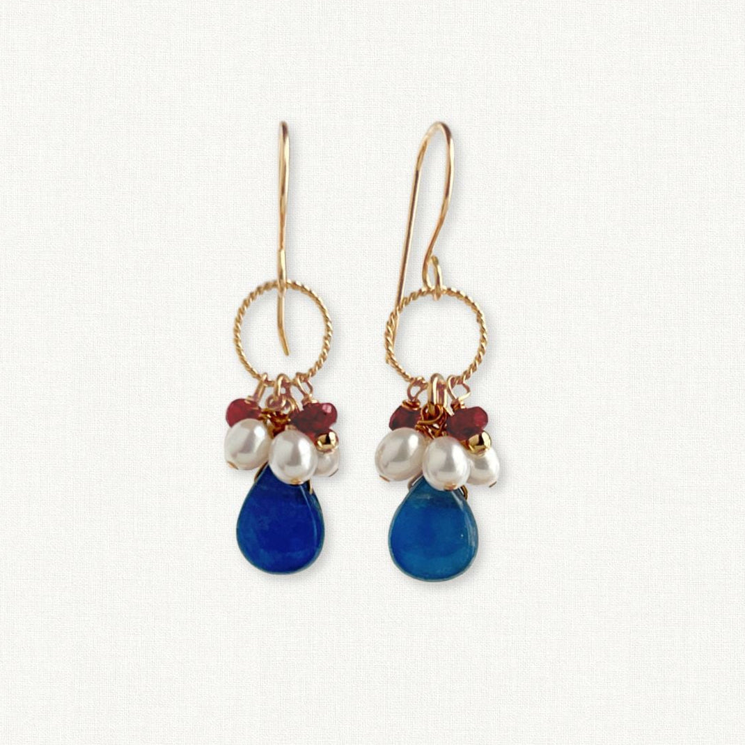 Pair of earrings with blue teardrop-shaped beads and pearl-like stones on a white background