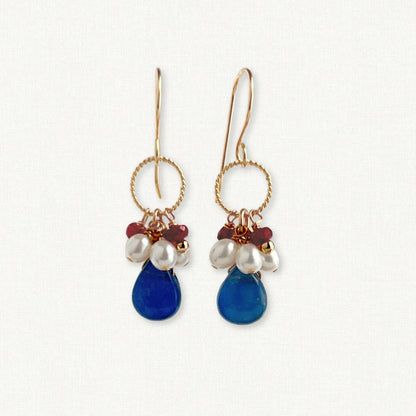 Pair of earrings with blue teardrop-shaped beads and pearl-like stones on a white background